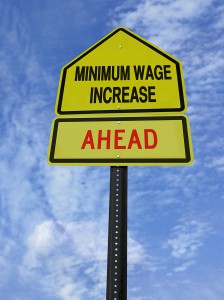 conceptual sign with words minimum wage increase  ahead over blue sky